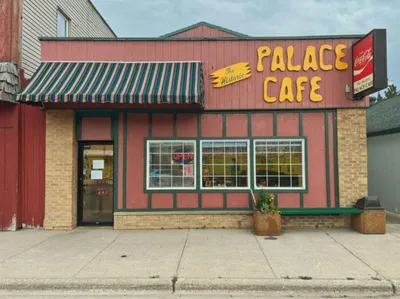 Exterior of Palace Cafe with yellow sign and striped awning on a small-town main street