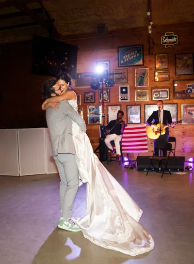Couple sharing first dance as live band performs in rustic venue decorated with vintage signs