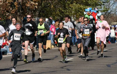 Costumed runners race down a sunny street during a Halloween fun run