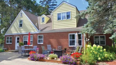 Brick and yellow-sided inn with outdoor patio seating and colorful flower gardens