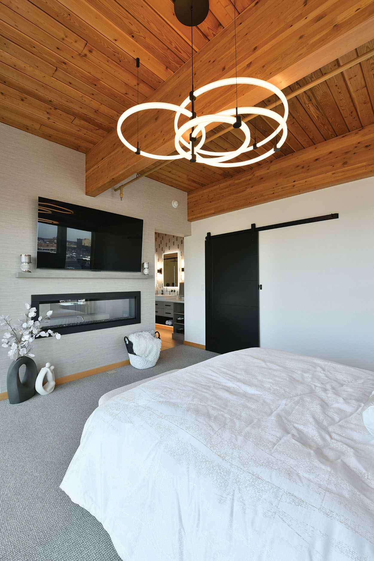Primary bedroom with wood ceiling and double-sided fireplace