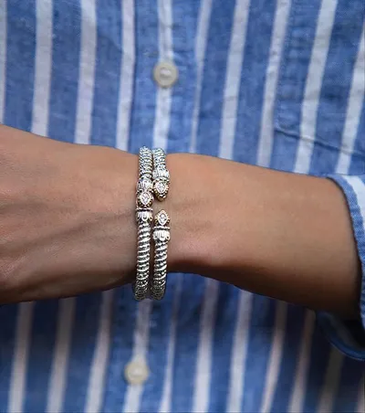 Two ornate silver cuff bracelets with small gemstone accents stacked on a wrist