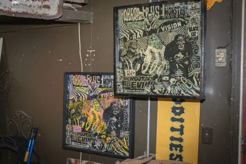 Two framed horror-themed collage artworks with bold text and psychedelic imagery on a dark wall