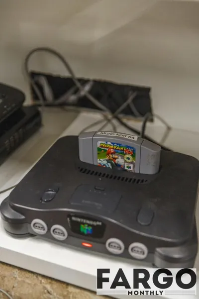Nintendo 64 console on a shelf with a Mario Kart 64 cartridge inserted