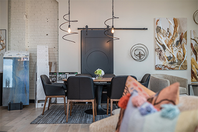 Modern dining area with black chairs, wood table, circular pendant light, and dark barn door