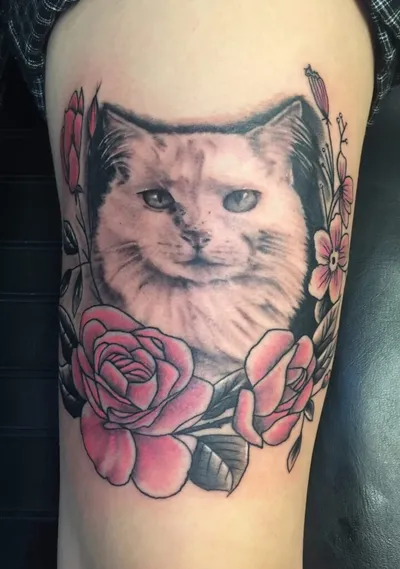 Tattoo of a white cat portrait surrounded by pink roses on an arm