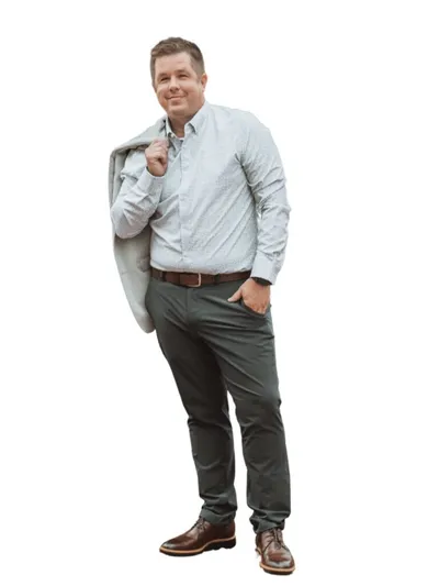 Man in light blue button-down and gray chinos drapes a blazer over his shoulder