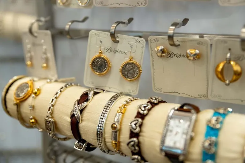 Bracelets and watches displayed on a cream roll stand beside Brighton earrings and rings on hanging cards