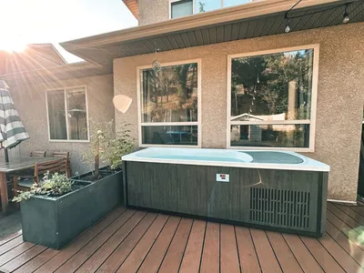 Hot tub with wood-panel siding on a deck beside a planter box