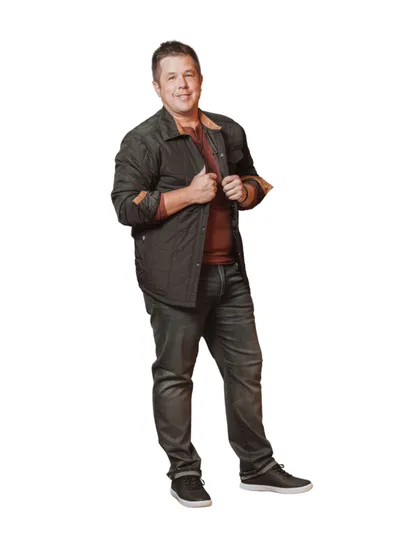 Smiling man in dark button-up shirt over rust tee and dark jeans, standing against white background