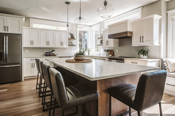 Modern kitchen with large dark wood island, white cabinetry, and pendant lights over bar stools