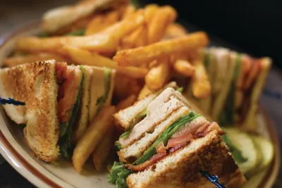 Club sandwich cut into triangles served with french fries on a diner plate