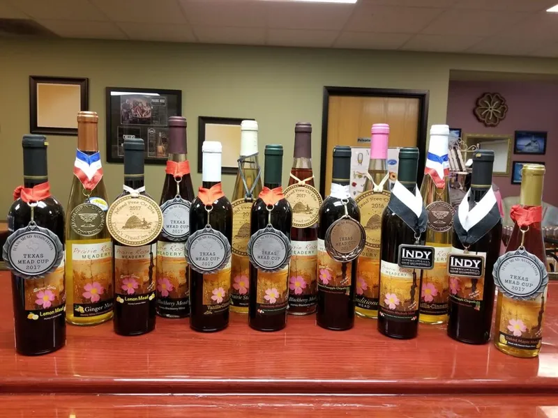 Row of award-winning mead bottles with Texas Mead Cup medals on a wooden bar