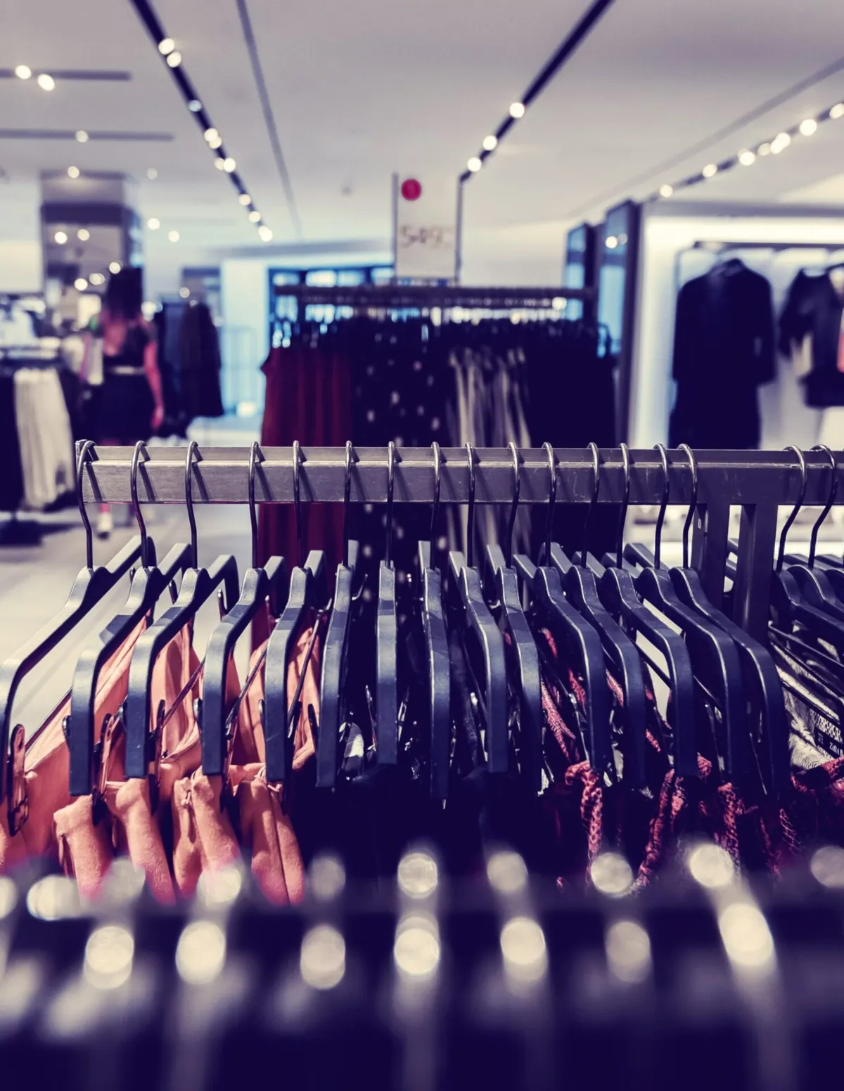 Clothing racks densely packed with garments on black hangers in a retail store