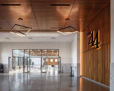 Modern venue lobby with wood-paneled walls, geometric pendant lights, and large '44' signage