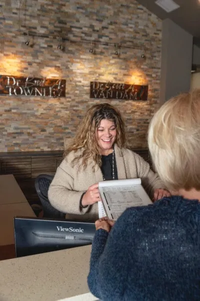 Smiling receptionist holding paperwork at a chiropractic office front desk